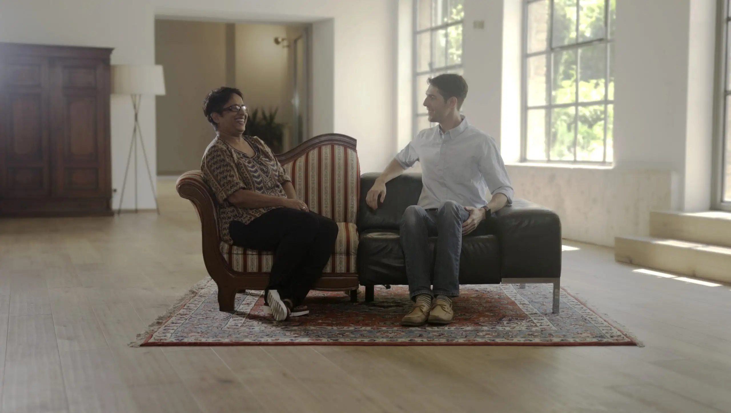 Two strangers with opposing views in conversation on their merged sofa