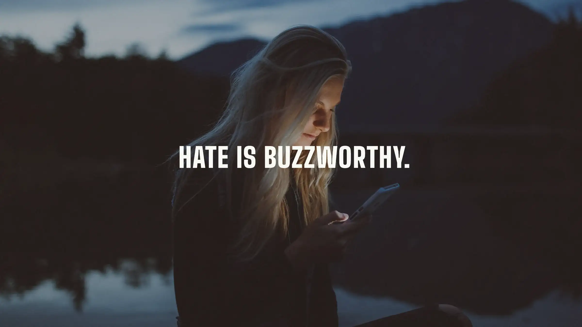 Slide: Hate is buzzworthy, over a woman lit by her phone at dusk