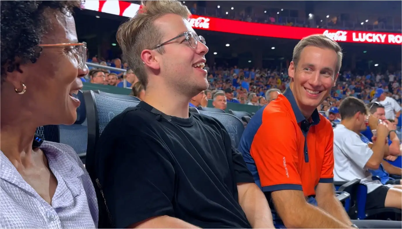 Kirby y Luke se ríen con Jared Young, de polo naranja, en las gradas del partido de los Royals
