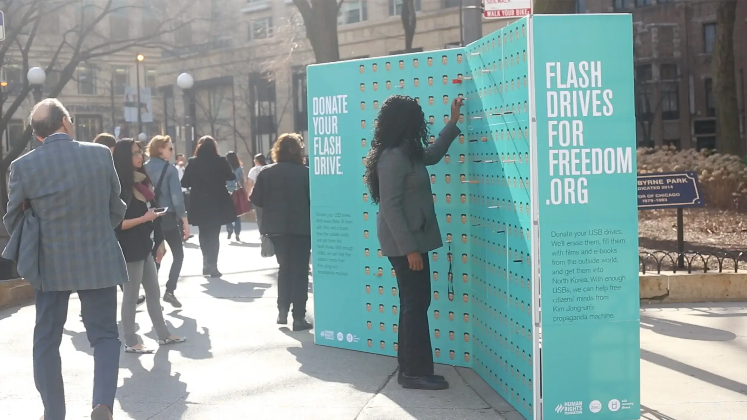 A passer-by plugs a drive into the Flash Drives for Freedom installation on a city street